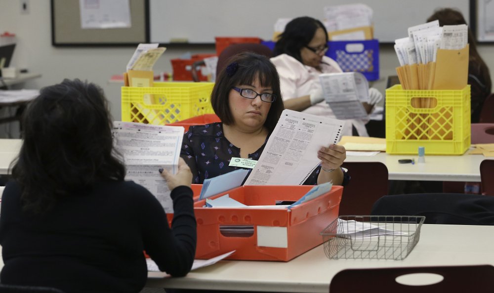 Temporary worker at the Sacramento Registrar of Voters, looks over a mail in ballot 